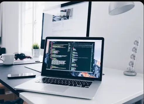 Werkplek met een laptop waarop programmeercode staat